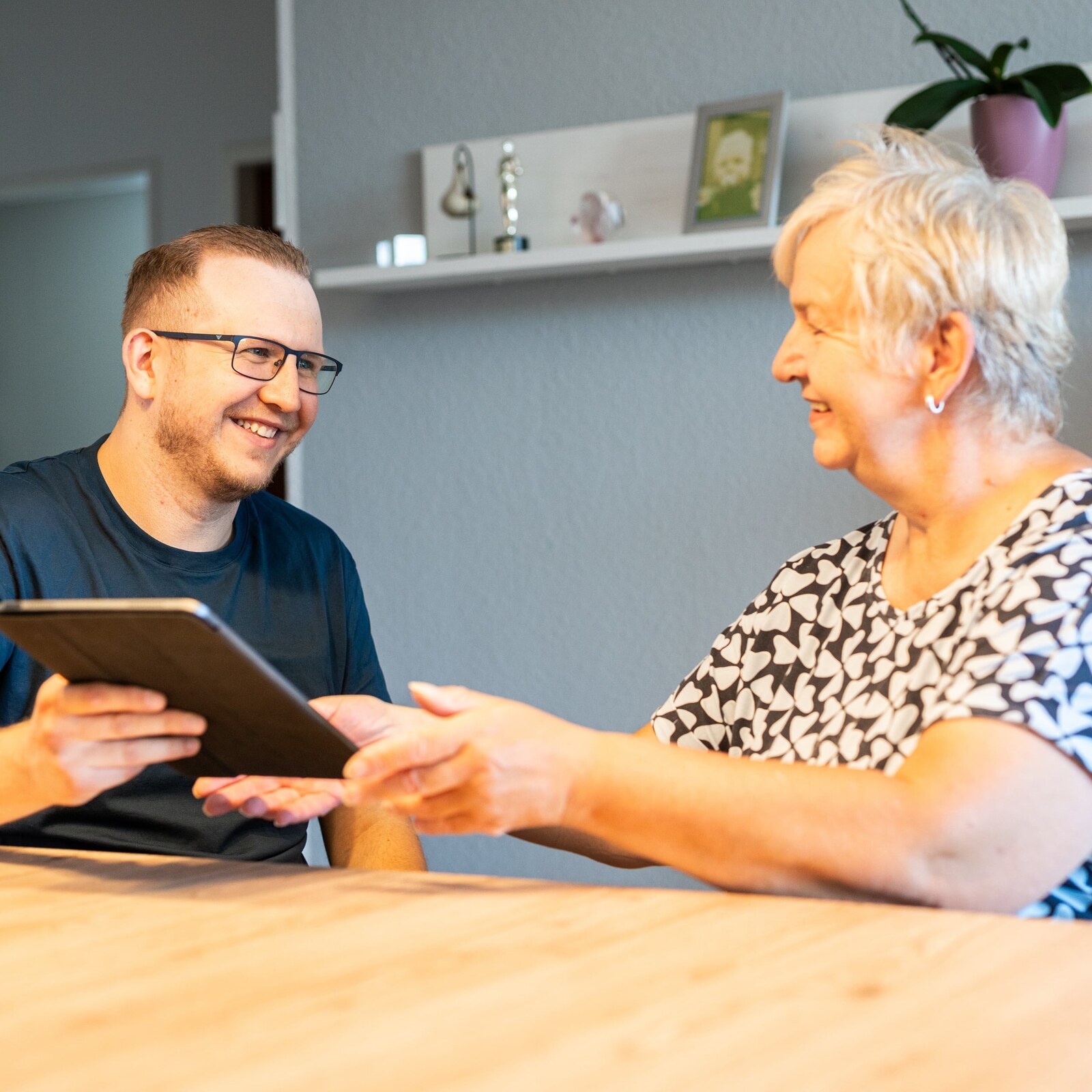 Jan Schlösser hilft einer Kundin an einem Tablet