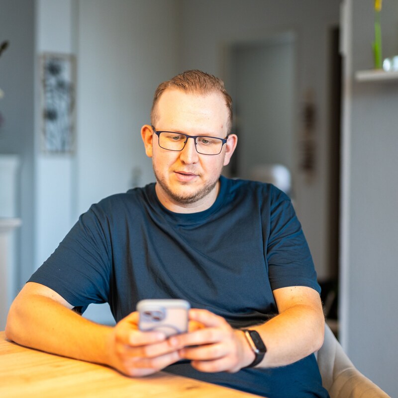 Jan Schlösser betrachtet ein Smartphone