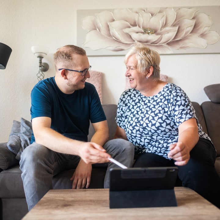 Jan Schlösser übt mit einer Kundin die Bedienung eines Tablets